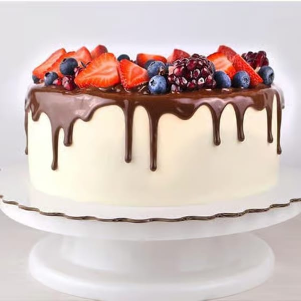 White cake with chocolate ganache dripping down the sides, topped with fresh strawberries, blueberries, and blackberries.